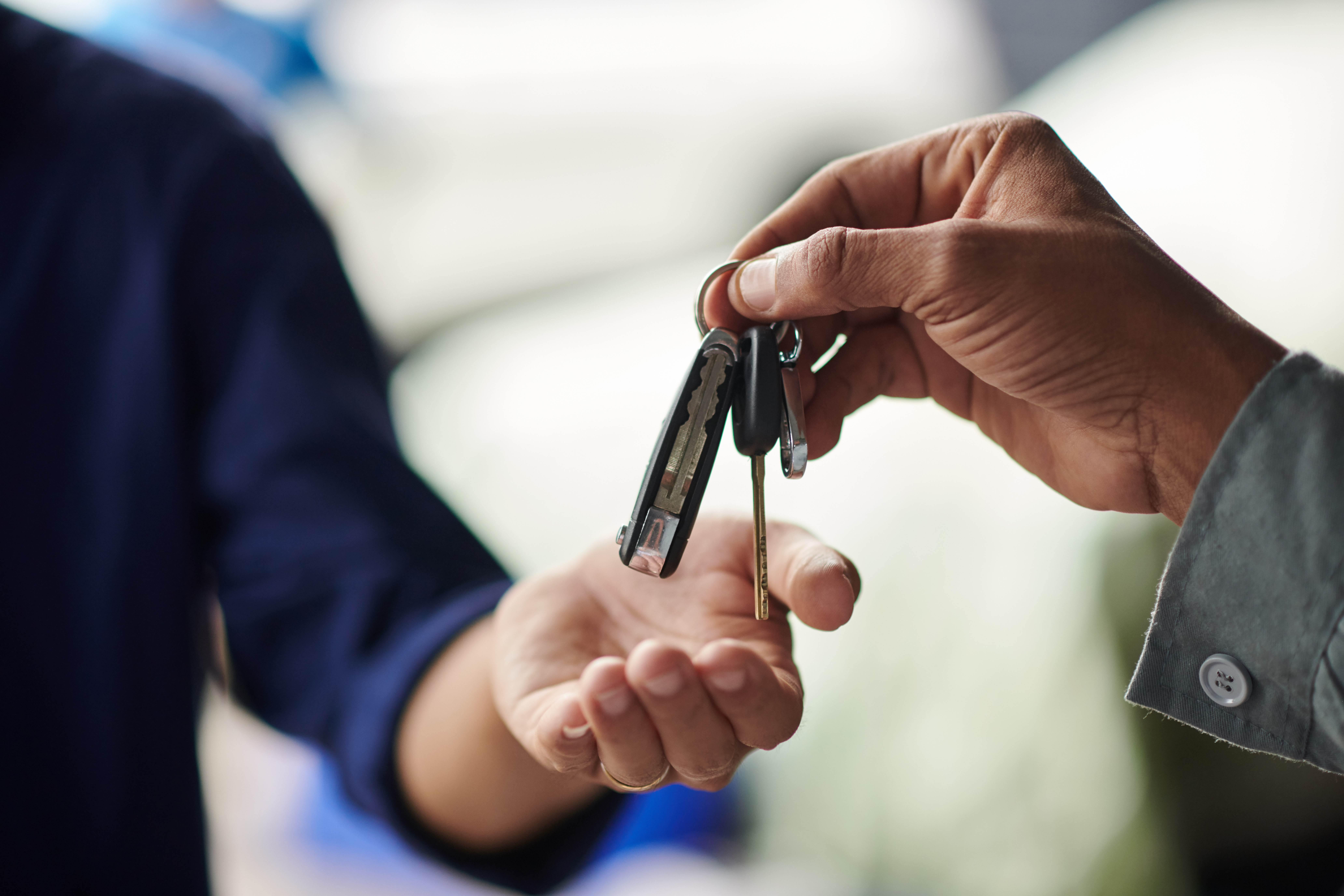 Closeup image of mechanic giving car keys to client after repairing it