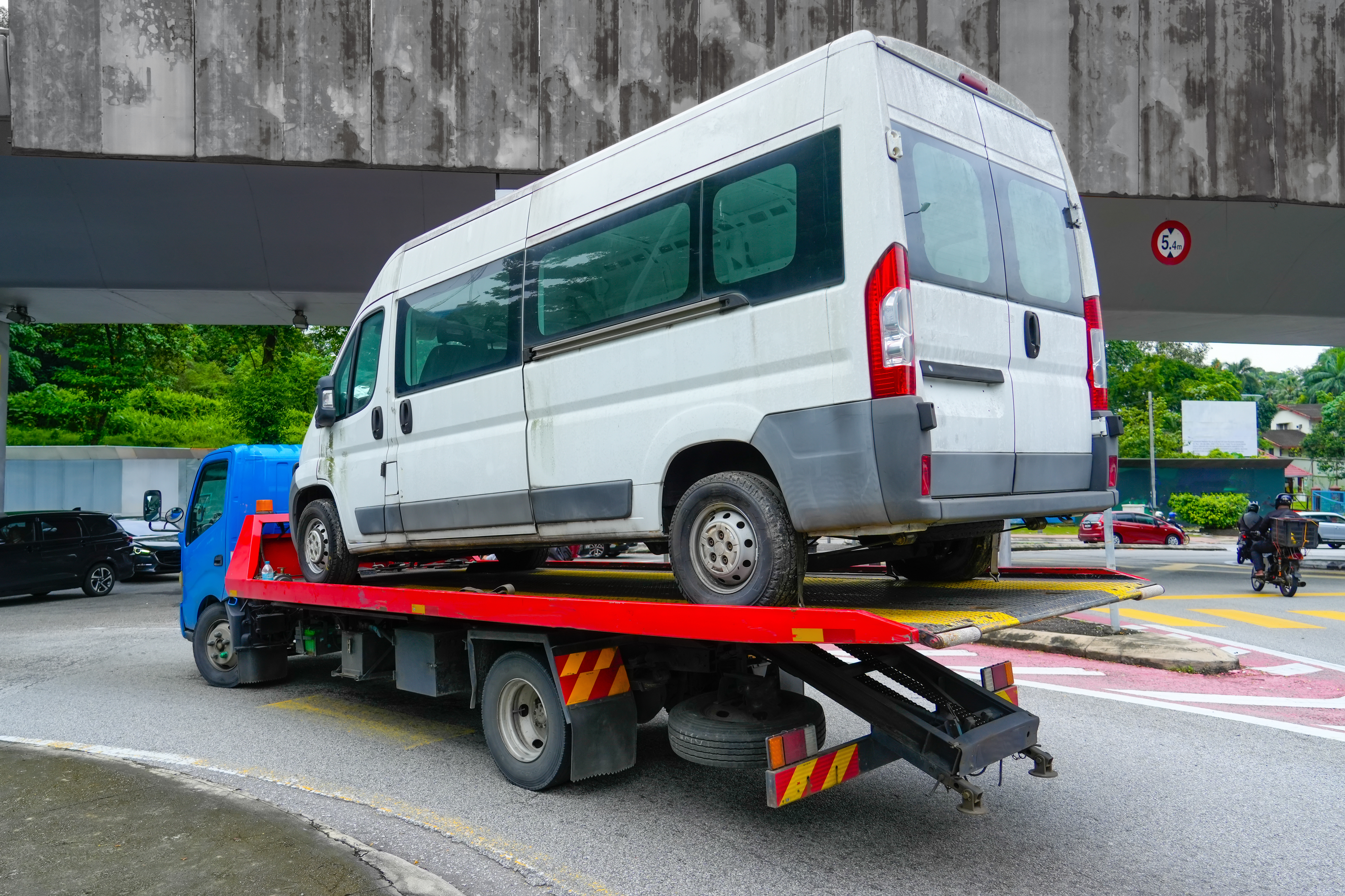 Carriage of a small minibus on the platform tow truck, back view.